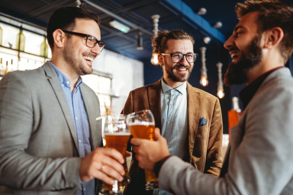 Business people drink beer after work in pub. Businessmen enjoy a beer