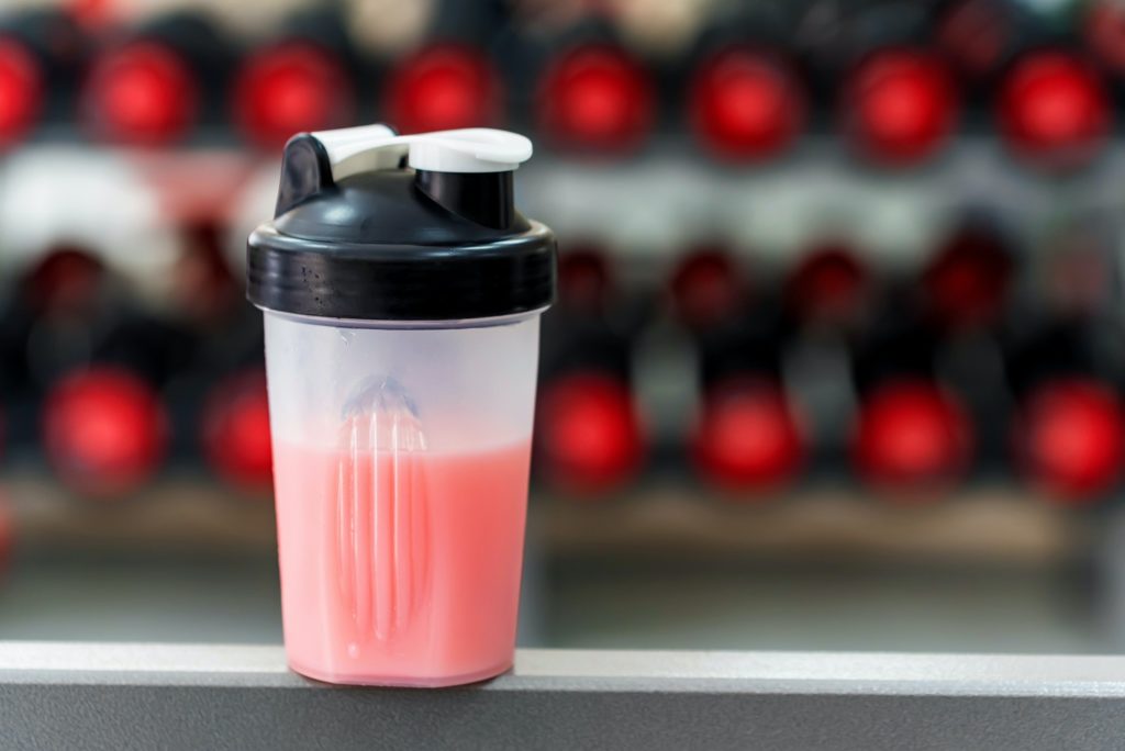 Plastic shaker with strawberry protein in gym