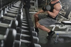 bodybuilder working out with bumbbells weights at the gym